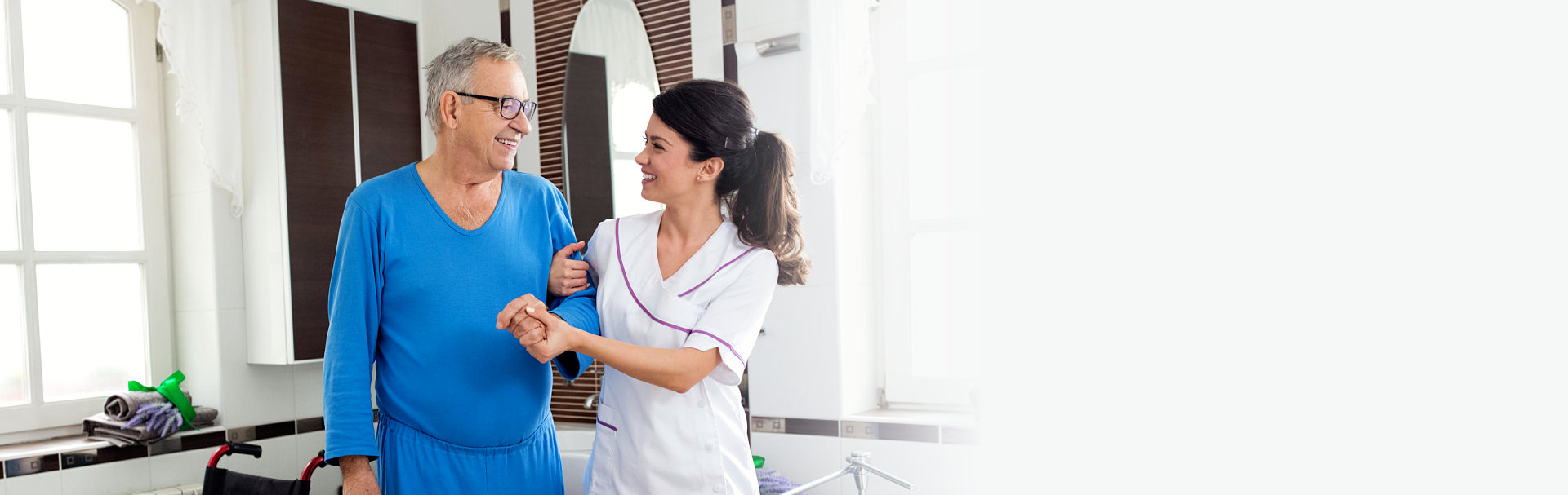 Young beautiful nurse helps senior man at the bathroom